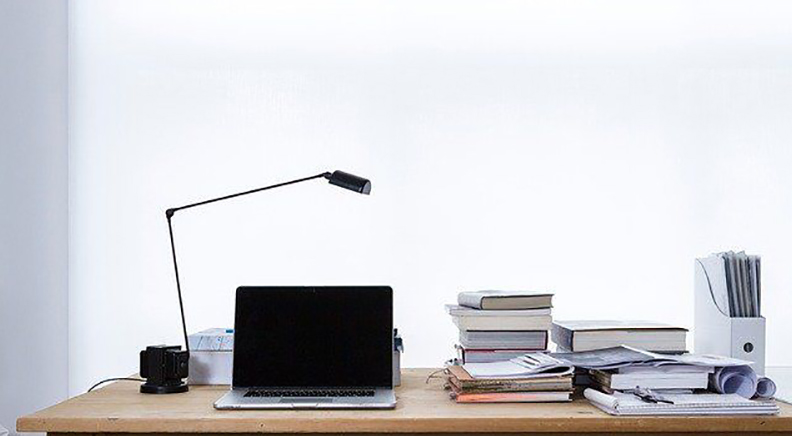 En svart och mycket stilren skrivbordslampa, ger ett modernt intryck