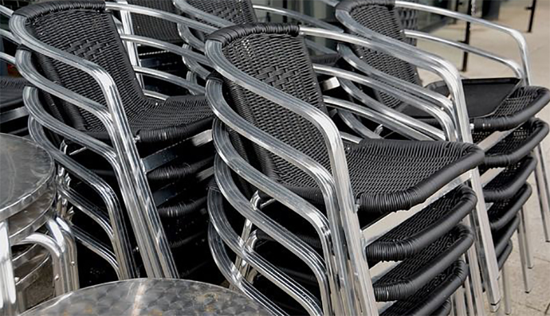 Stapelbara stolar i svart rotting och metall, en klassiker på uteserveringen