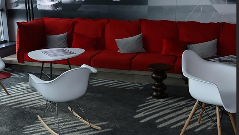 En röd bekväm soffa tillsammans med vita fåtöljer